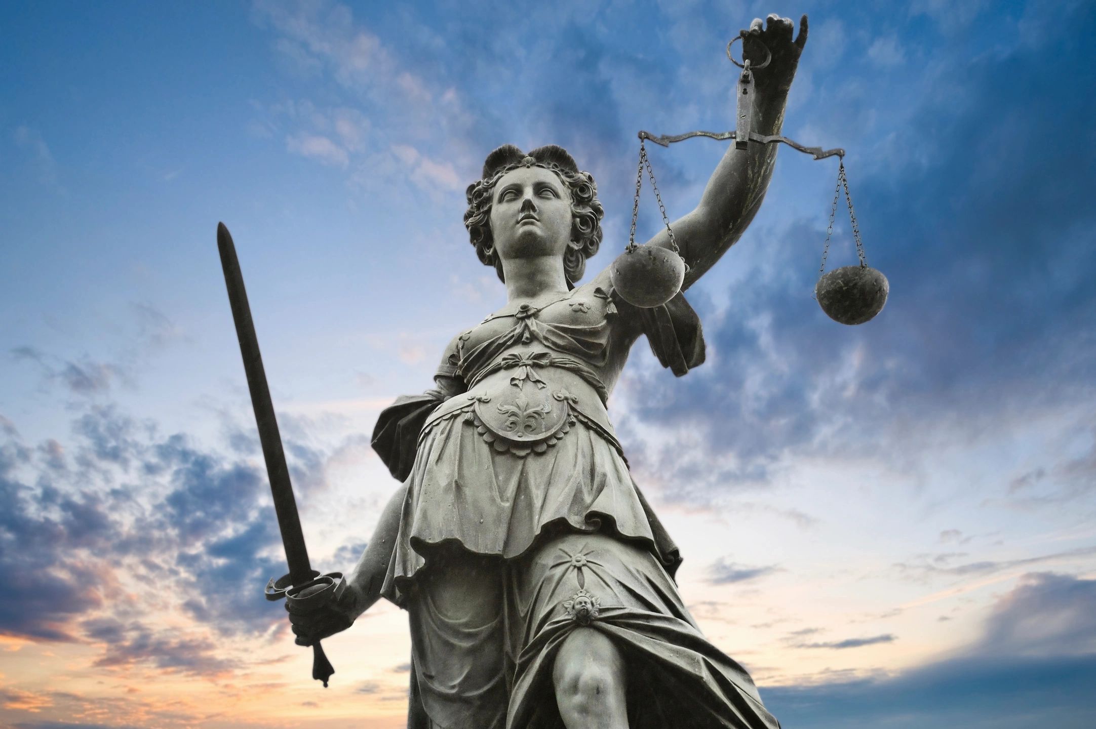 Lady Justice statue against dramatic sky